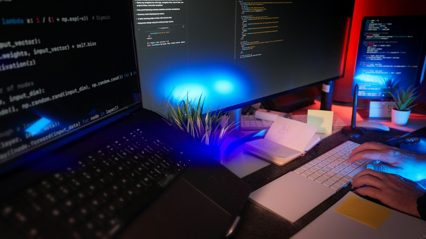 Monitores de programación en una estación de trabajo con luz azul y código en pantalla